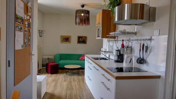Une cuisine moderne dotée d’un îlot central intégré, d’appareils électroménagers en acier inoxydable et d’un porte-ustensiles suspendu.