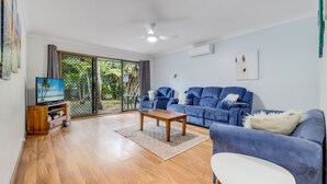 A living room with a blue sofa, a wooden coffee table, and a television on a wooden stand. - Cresta 1 Crescent Head (Crescent Head)
