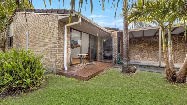 A modern house with a brick exterior, a wooden deck, and a glass door leading to an interior space.
