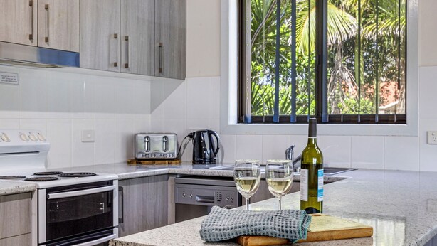 A modern kitchen with a large window, a toaster, a kettle, and two glasses of white wine on the counter. - Cresta 1 Crescent Head (Crescent Head)