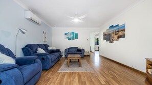 A modern living room with two sofas, a coffee table, and a ceiling fan.