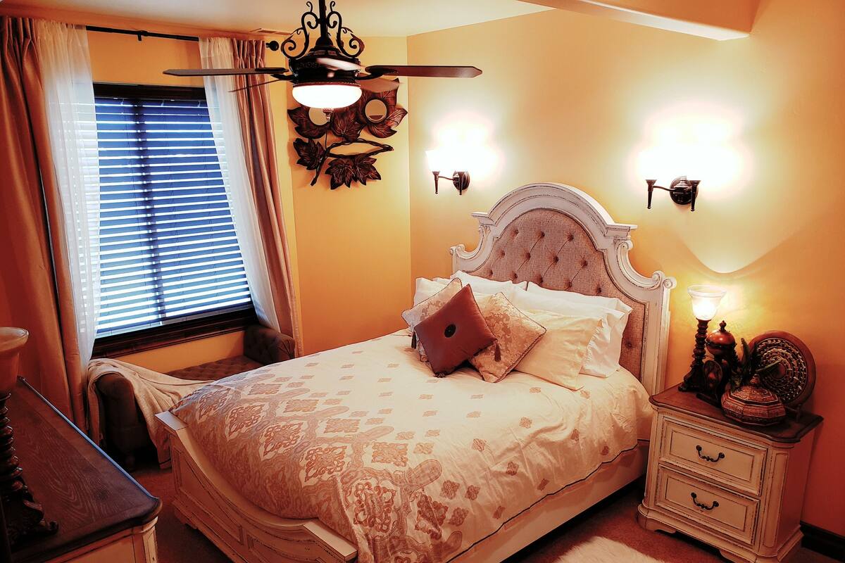 A bedroom with a bed, nightstands, a dresser, and a ceiling fan.