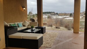 Ein überdachter Patio-Bereich mit einer Sofagarnitur, einem Couchtisch und einer Lampe.