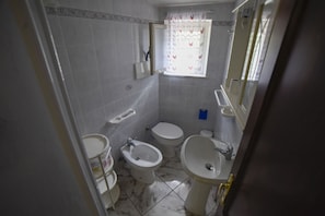 Un baño con inodoro, bidé y lavamanos.