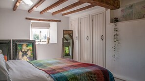A bedroom with a bed, a window with a view, a wardrobe, and a mirror. - Bentleys - Three Bedroom Cottage, Sleeps 6 (Kingham)