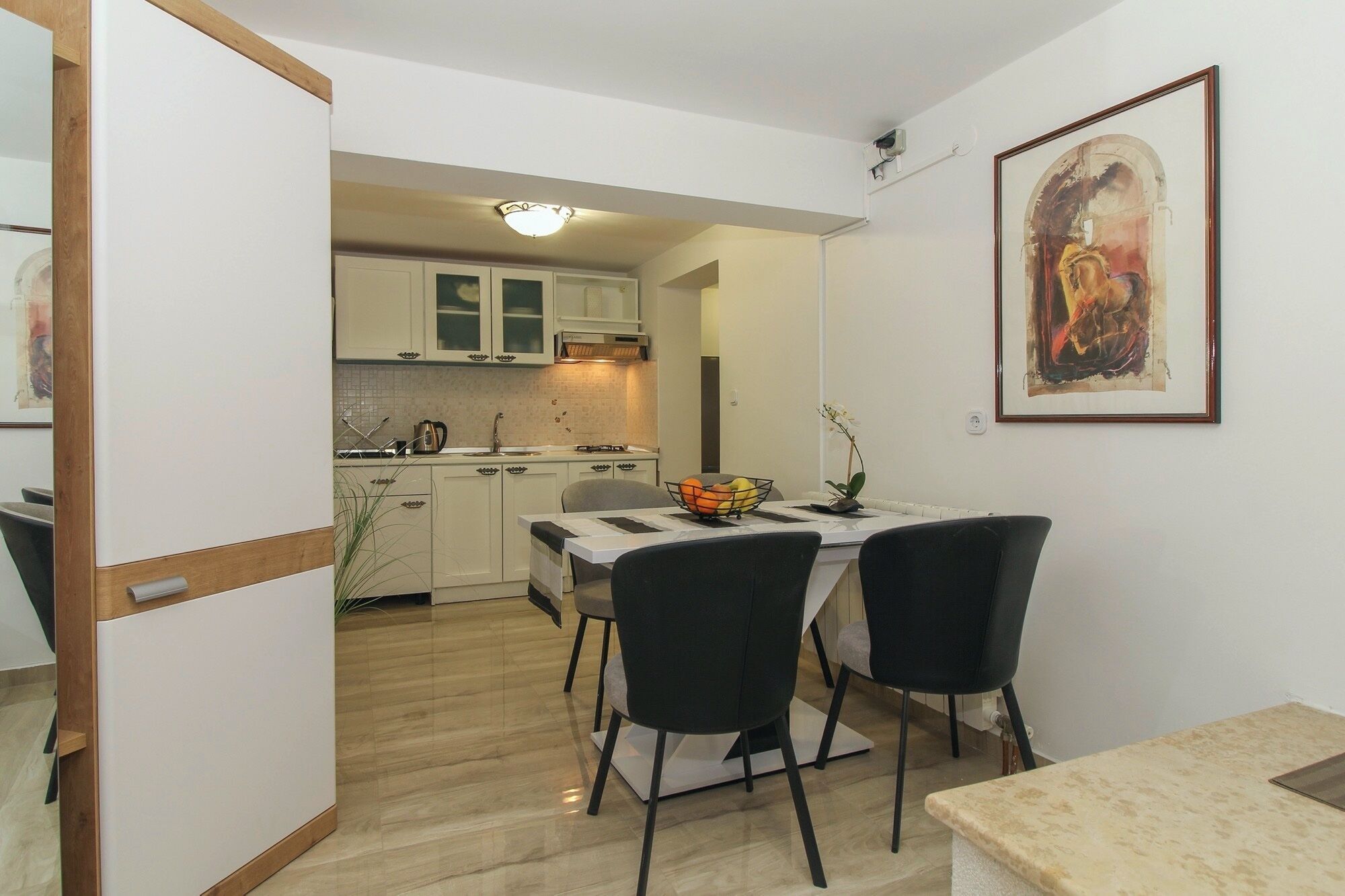 A compact kitchen with white cabinets and a dining area with a table and chairs.