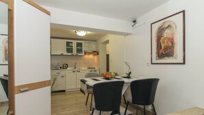 A compact kitchen with white cabinets and a dining area with a table and chairs.