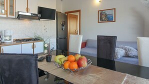 A modern kitchen with a coffee maker, a fruit bowl on the counter, and a dining area with a sofa and chairs. - Aida in Poreč - Istrien / Aida in Poreč - 1 Appartement für 4-6 Personen AP7 (Porec)