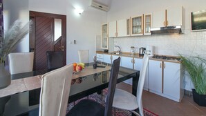 A modern kitchen with white cabinets, a gas stove, and a dining area with a glass table and chairs. - Aida in Poreč - Istrien / Aida in Poreč - 1 Appartement für 4-6 Personen AP7 (Porec)