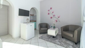 Un salon moderne avec un canapé blanc, un fauteuil gris, une petite table basse et un vase décoratif contenant des fleurs roses.