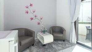 Un salon moderne avec deux fauteuils, une table d’appoint blanche et un vase rempli de fleurs.