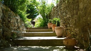 En stentrappe med terracottakrukker og grønne planter.