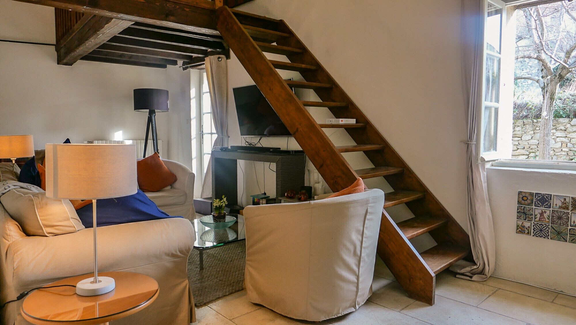 A living room with a wooden staircase, a sofa, a coffee table, and a television.