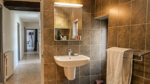 Une salle de bain avec un lavabo blanc, un miroir et un porte-serviettes.