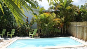 A rectangular swimming pool with a stone tile deck, surrounded by green chairs and tropical plants. - Coco Bungalows. Bungalows 2 / pers sea at 100m (Ste Rose)