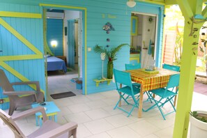 A room with a bed, a table with chairs, and a small kitchen area.