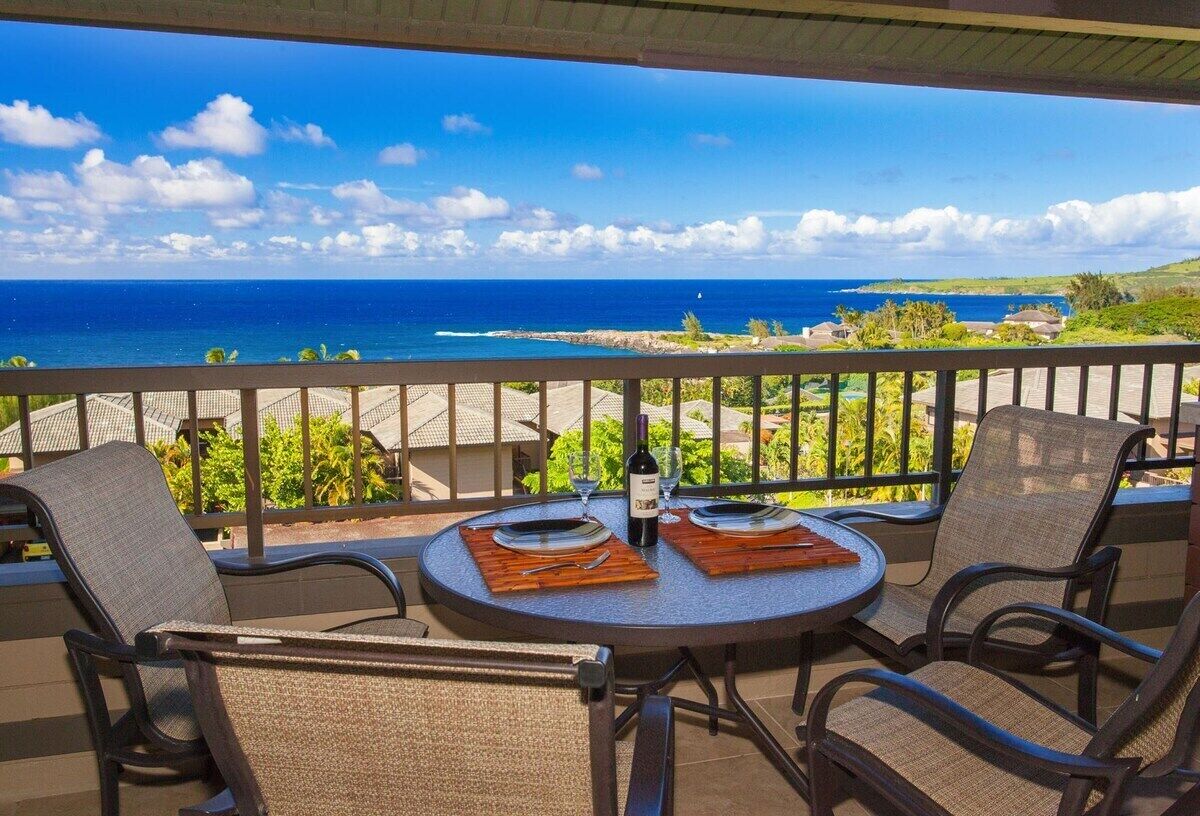 Un balcon avec une table dressée pour deux personnes, offrant une vue sur la côte.