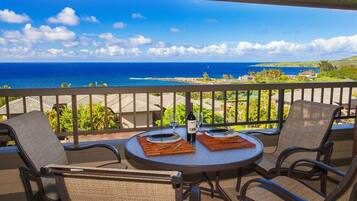 Un balcon avec une table dressée pour deux personnes, offrant une vue sur la côte.