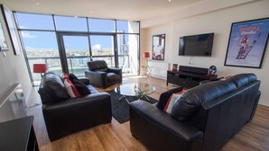 A modern living room with a large window, a flat-screen TV, and a leather sofa. - Lancefield Quay - SECC & Hydro Arena, parking available (Glasgow)