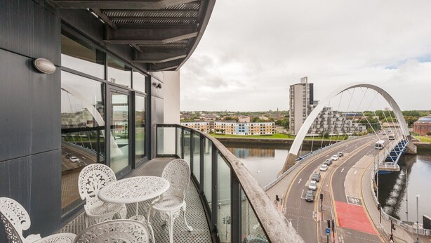 A balcony with white metal chairs and tables overlooking a cityscape, a river, and a bridge. - Lancefield Quay - SECC & Hydro Arena, parking available (Glasgow)