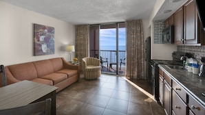 A compact living space with a sofa, armchair, dining table, and kitchenette. - Oceanfront Executive King Suite w/ View + Official On-Site Rental Privileges (Myrtle Beach)
