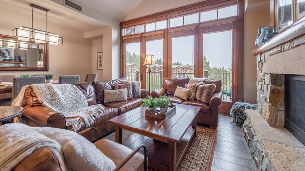 A spacious living room with leather sofas, a wooden coffee table, and a stone fireplace. - Iron Horse North - Luxury in the Northstar Village! (Truckee)
