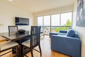 Relax in this stylish living room with a flat-screen TV and a comfortable sofa, perfect for unwinding with a view of the outdoors.