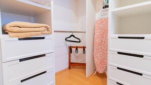 En walk-in-garderob med vita lådor och en klädstång.