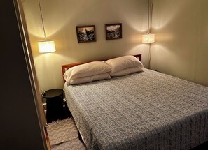 Een slaapkamer met een bed, twee wandlampen en twee ingelijste foto's.