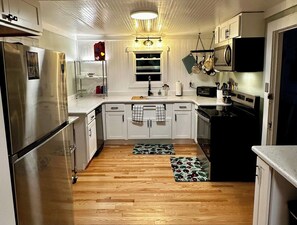 A kitchen with white cabinets, stainless steel appliances, and a wooden floor.