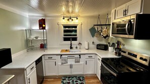 A modern kitchen with white cabinets, a stainless steel oven, a microwave, and a wooden countertop. - Rivers Edge Cabin, Swimming, Tubing, Fishing, Fire Pit, Grill, Wi-Fi, Relaxing! (Burnsville)
