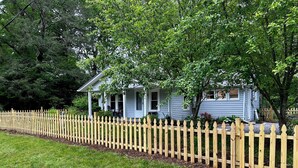 A house with a wooden picket fence, a porch, and a well-maintained lawn. - Rivers Edge Cabin, Swimming, Tubing, Fishing, Fire Pit, Grill, Wi-Fi, Relaxing! (Burnsville)