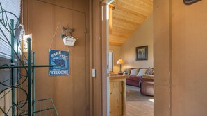 Un interior de madera con un cartel de bienvenida que dice 'Bare Feet', una escalera y una sala de estar con sofá y lámpara.