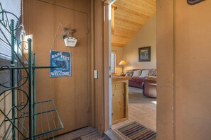 Cozy living area with a couch and lamp, featuring a wooden door and a metal ladder.
