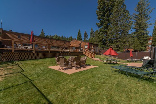 A backyard with a wooden deck, outdoor seating, and a barbecue area.