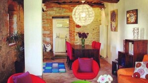 Un salon chaleureux avec une cheminée, des fauteuils rouges, une table basse et une bibliothèque.