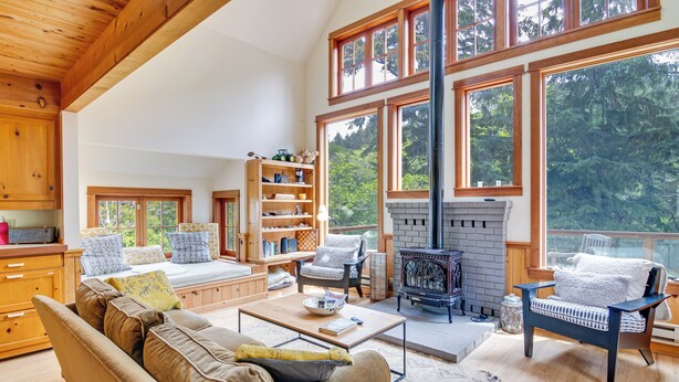 A spacious living room with a large window, a fireplace, and a cozy seating area. - River to Breakers - River View (Yachats)