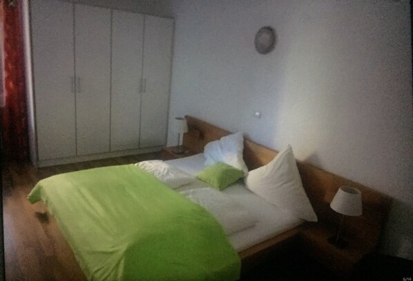A bedroom with a bed, pillows, a bedside table with a lamp, and a wardrobe.