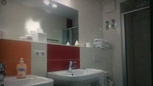 Un baño con dos lavamanos, un inodoro y un espejo.