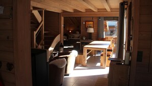 Interior de uma cabana de madeira com escadas, área de jantar e sala de estar.