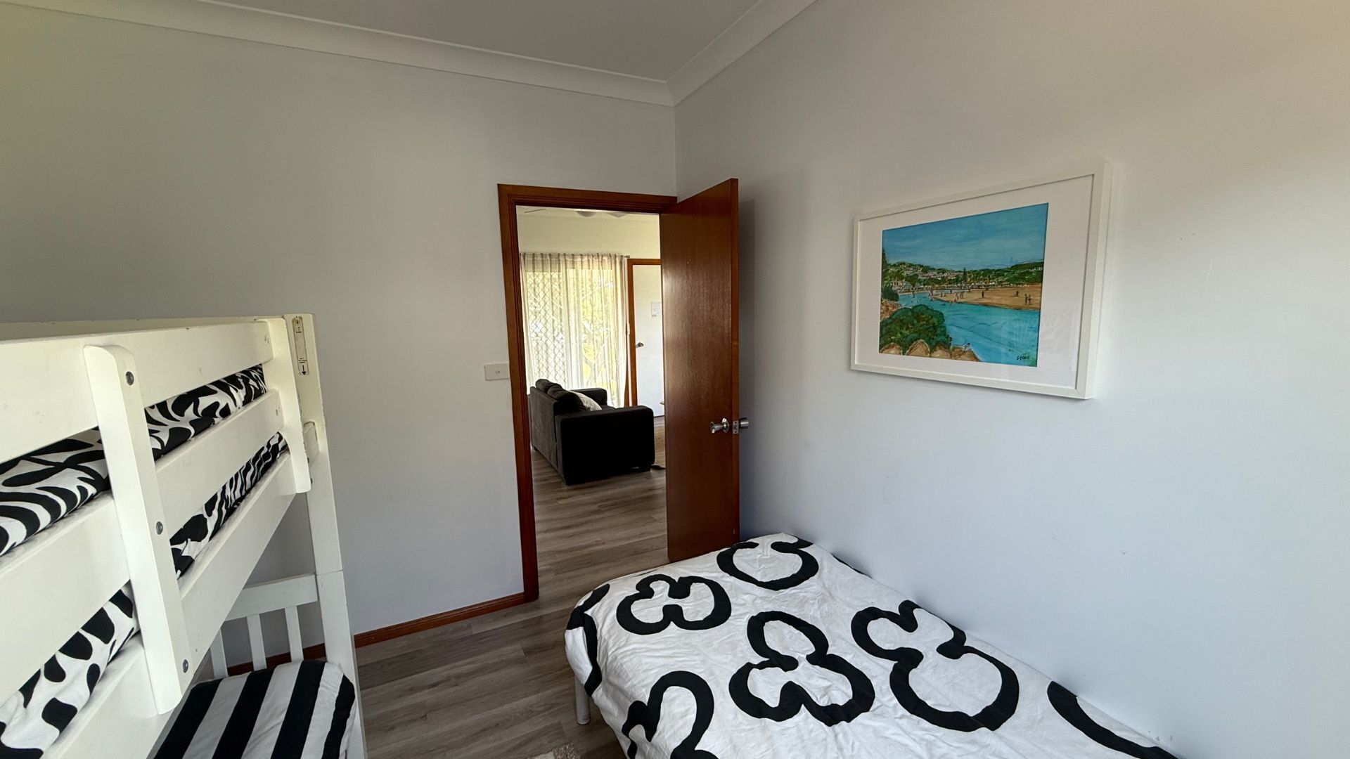 Une chambre avec un lit, un lit superposé et une porte donnant sur une autre pièce.