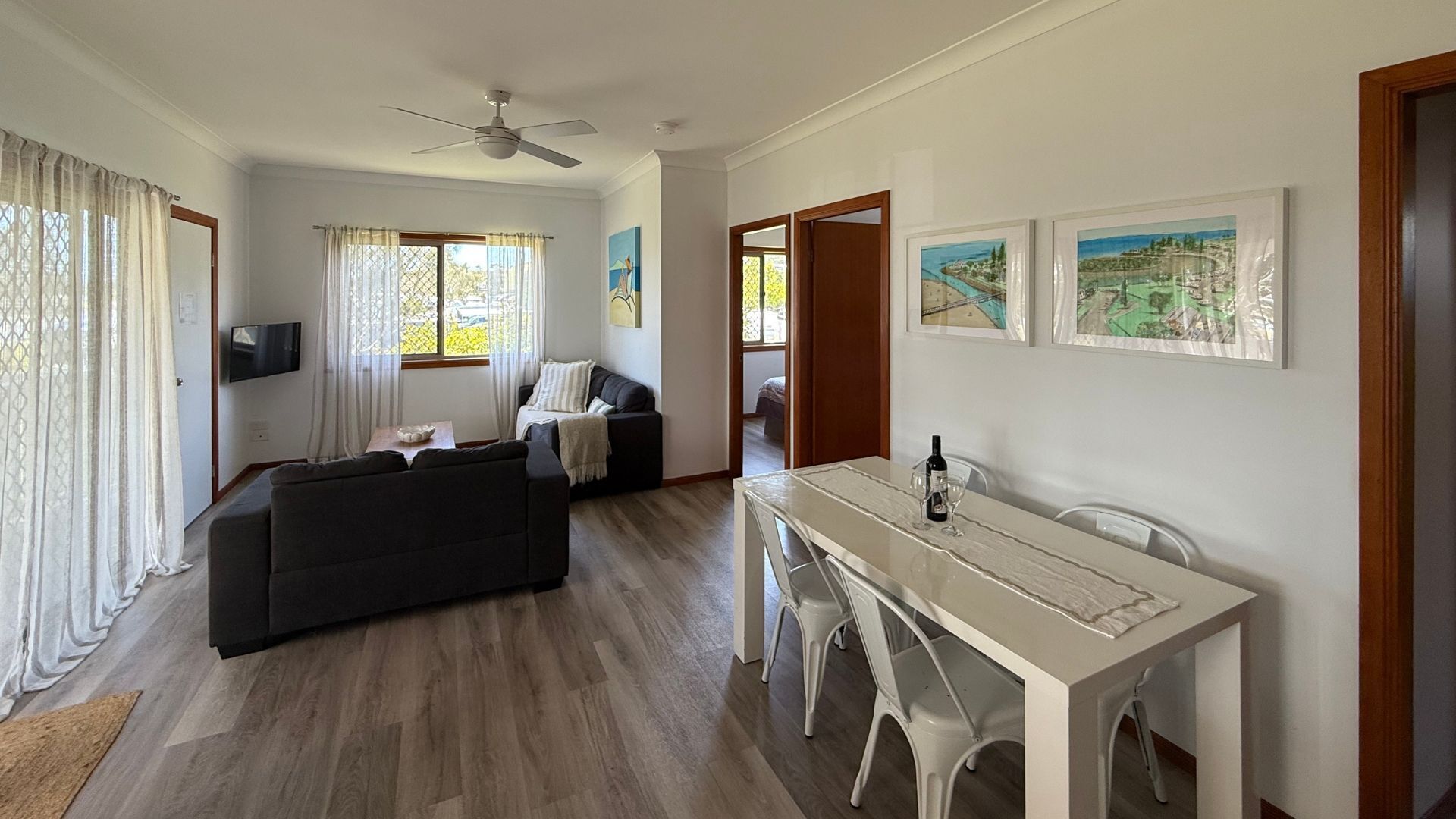 Un salon avec un canapé, une table à manger et des chaises, un ventilateur de plafond et un téléviseur.