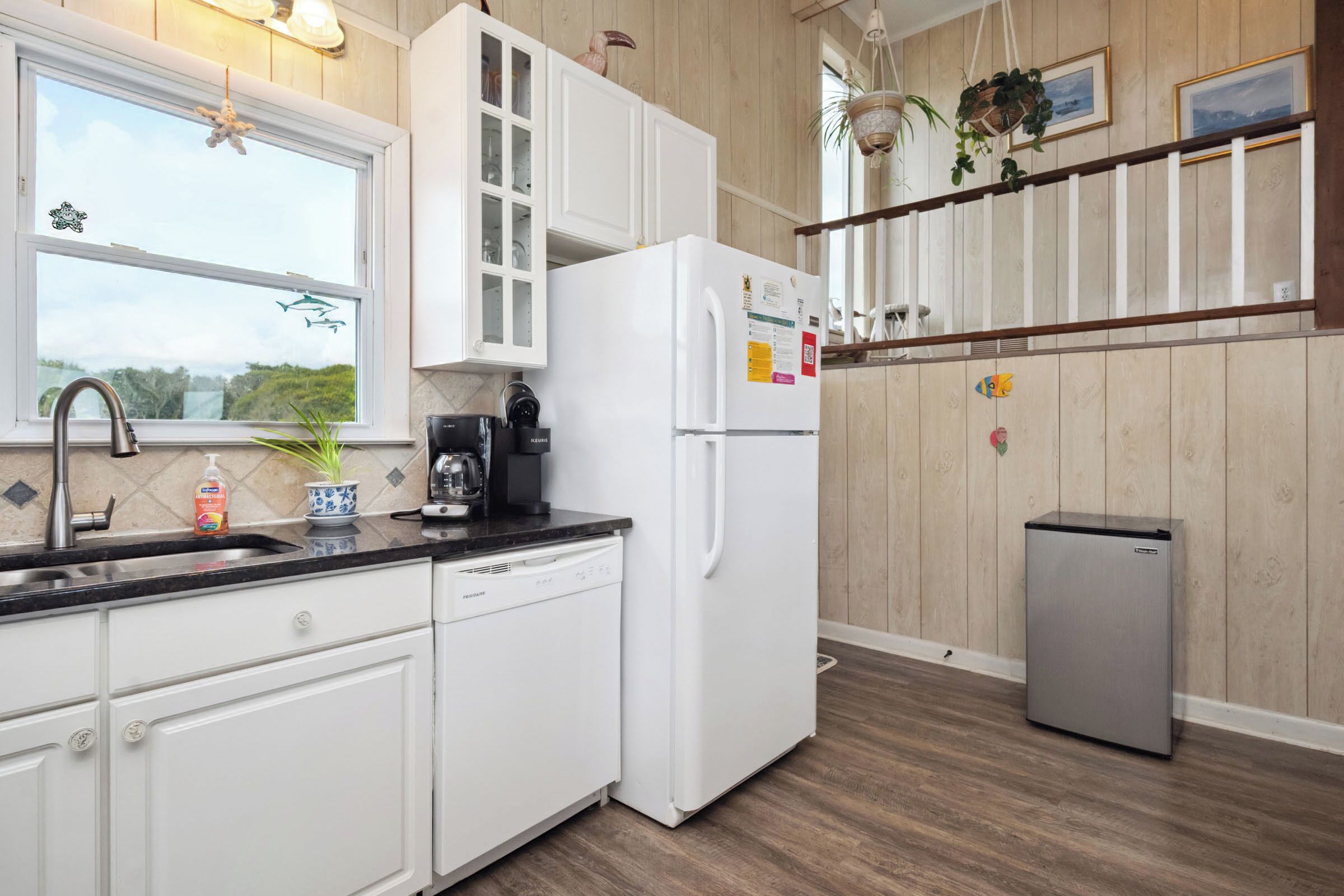 Una cocina moderna con armarios blancos, un refrigerador de acero inoxidable, lavavajillas y cafetera.