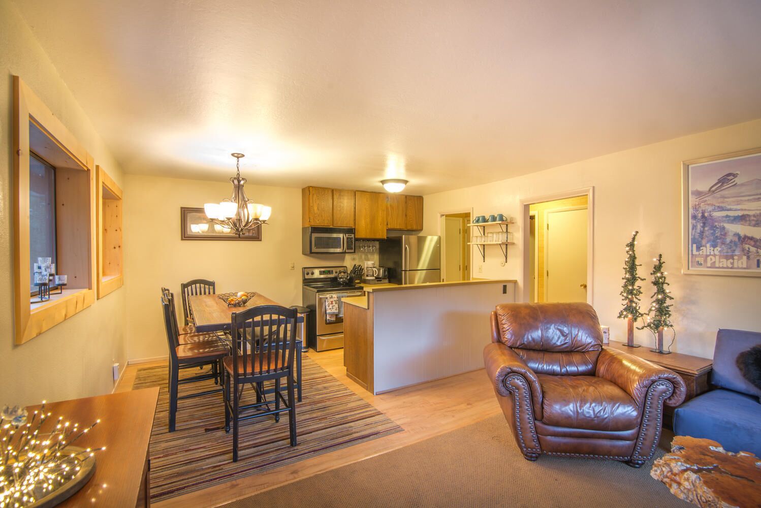 A compact living space with a dining area, kitchen, and a leather armchair.