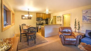 A compact living space with a dining area, kitchen, and a leather armchair.