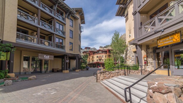 A multi-story hotel with balconies, a stone facade, and a paved courtyard.