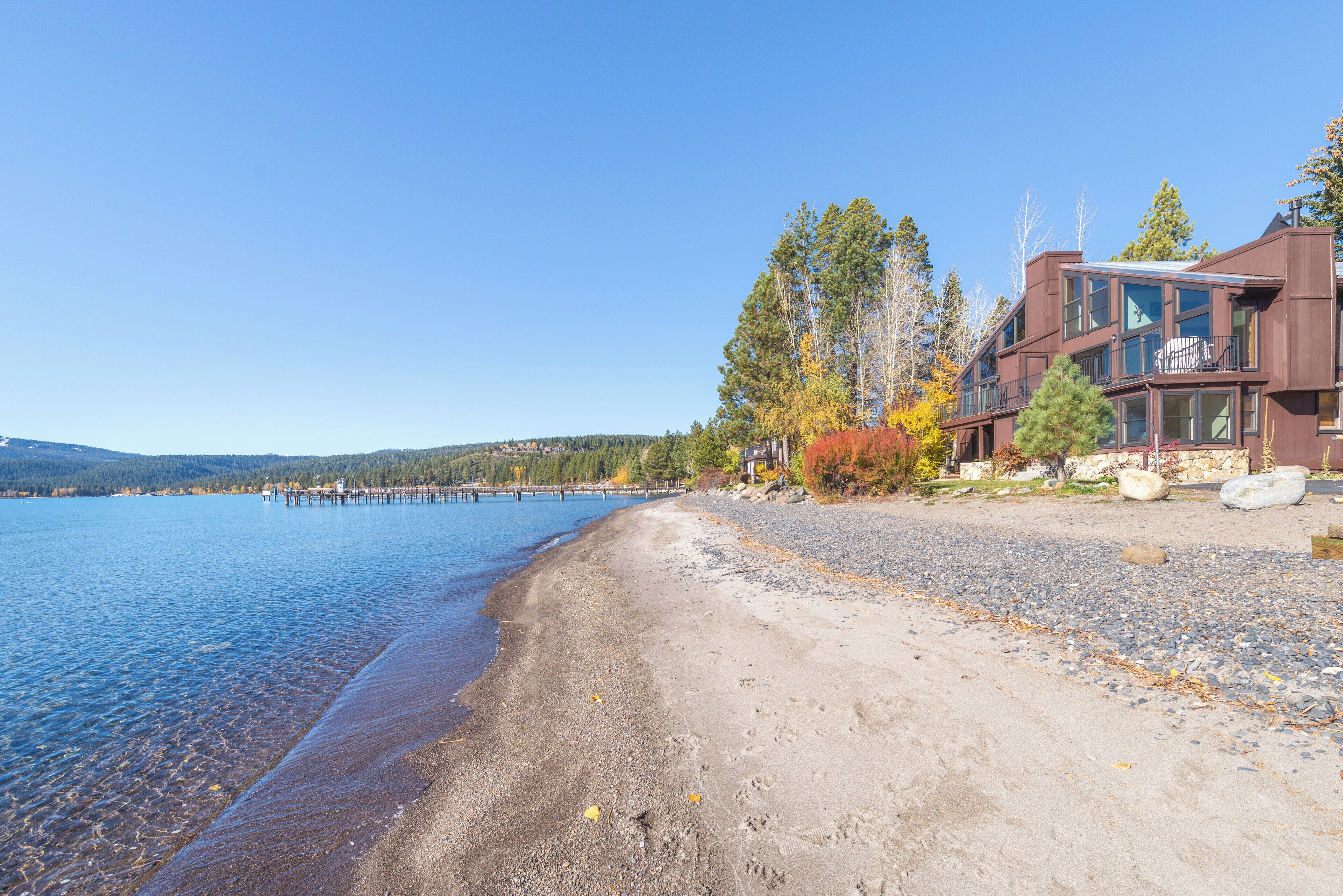 Une propriété au bord du lac, dotée d’une plage de sable, d’une eau cristalline et d’un bâtiment en bois avec des balcons.
