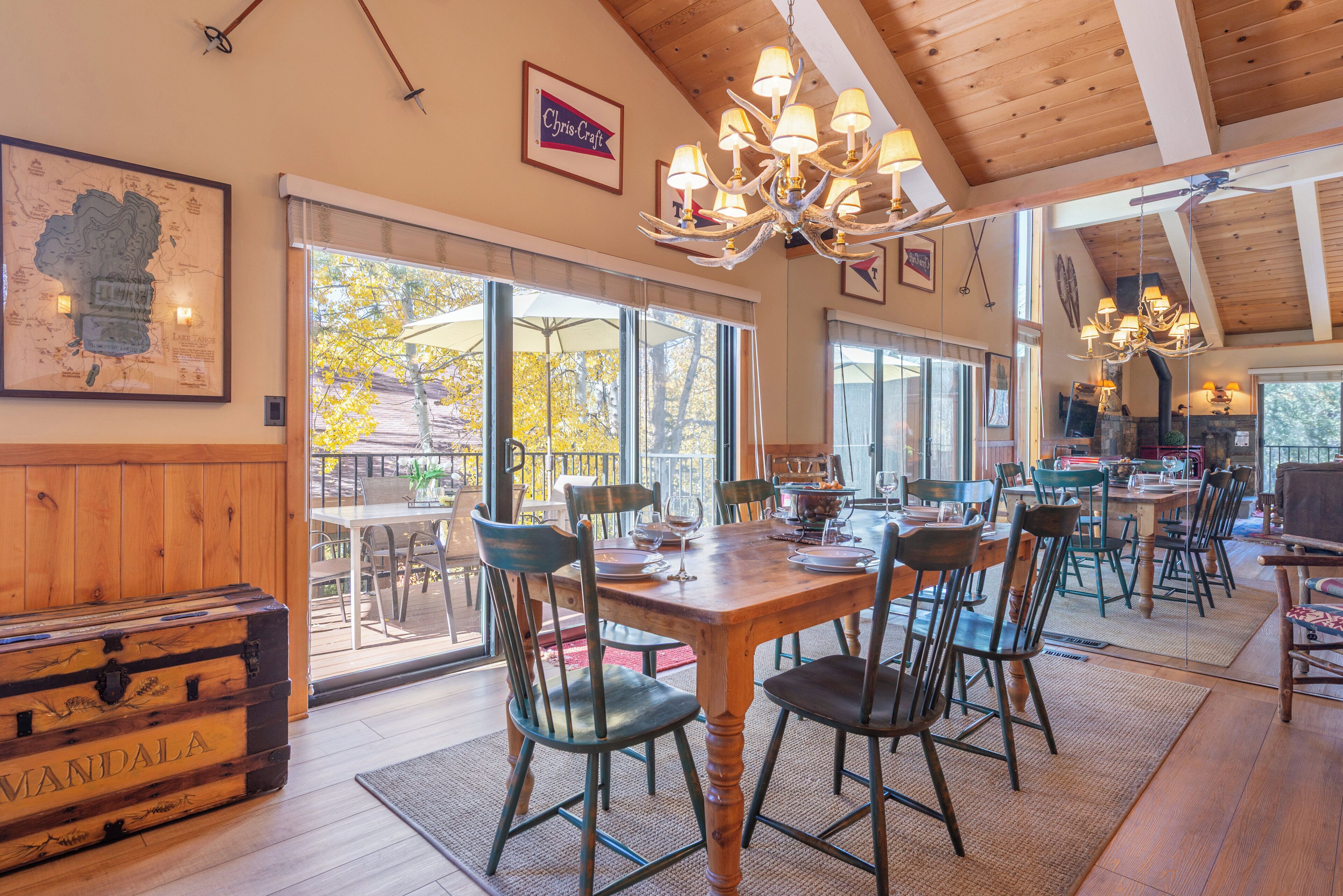 Un'area pranzo con tavolo e sedie in legno, un lampadario e vista sull'esterno.