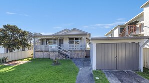 Ein Wohnhaus mit überdachter Veranda, Garage und gepflegtem Rasen.