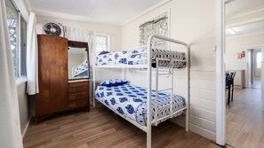 Ein Schlafzimmer mit Etagenbett, einem Holzschrank, einem Spiegel und einer gemusterten Bettdecke.